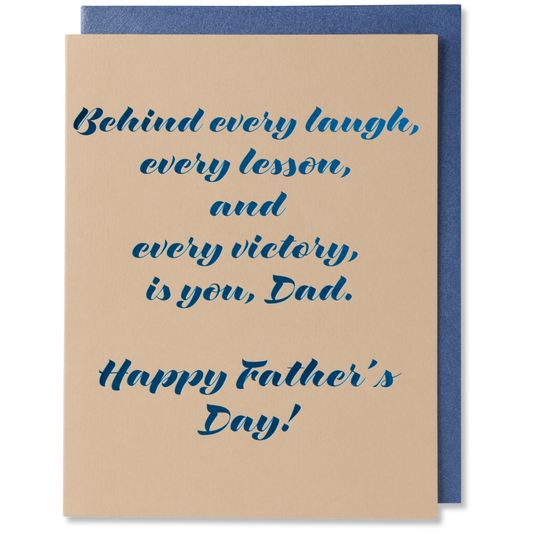 Father’s Day card with navy blue foil on tan paper, reads 'Behind every laugh, every lesson, every victory, is you, Dad,' shown with metallic blue envelope